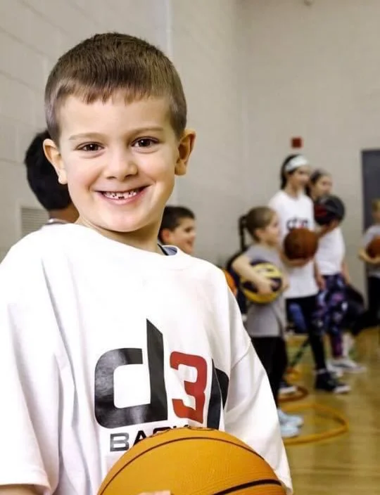 Young athlete smiling and holding a basketball at D3P Sports & Community.